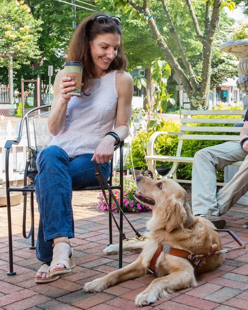 Close-up of a woman looking affectionately down at her golden retriever guide dog